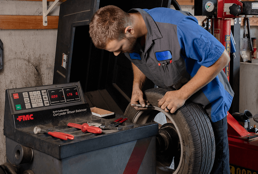 Autosmith technician examining tires for wear and tear