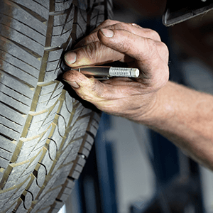 Autosmith technician checking tire tread for wear and tear